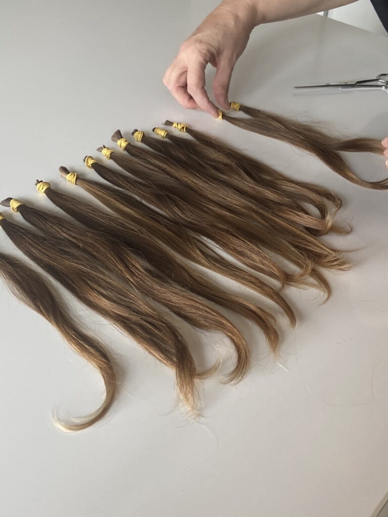 Mèches de cheveux coupées, attachées par des élastiques, prêtes pour la fabrication : des cheveux naturels cousus sur un bandeau noir